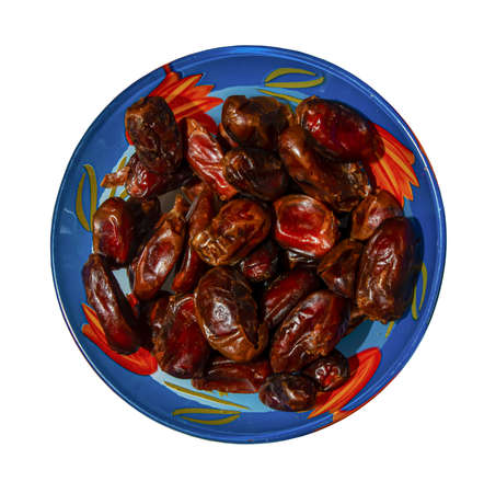 Dates in a blue bowl. isolated on white background. top view.の写真素材