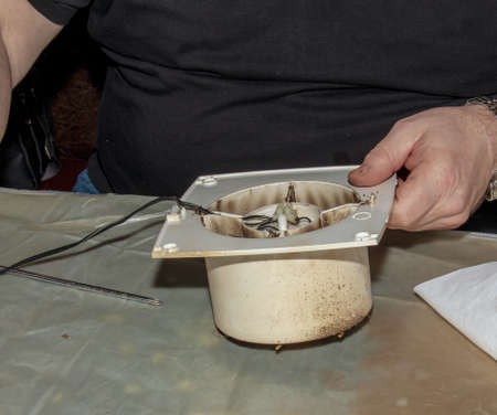 Close-up of a very dirty kitchen exhaust fan. Fan before preventive cleaning and washing. Disassembly process.の写真素材