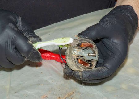 Cleaning a very dirty kitchen exhaust fan from dirt with a brush. A man cleans the parts of a fan with a brush.の写真素材