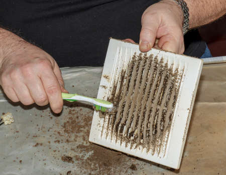 Cleaning a very dirty kitchen exhaust fan from dirt with a brush. A man cleans the parts of a fan...