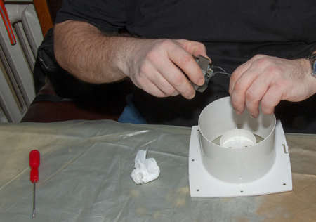 The process of assembling the kitchen exhaust fan after cleaning the wash. A man works with a...
