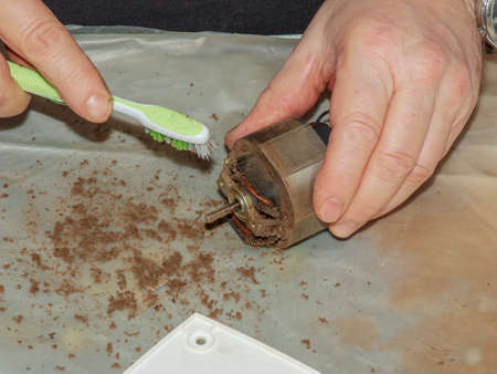 Cleaning a very dirty kitchen exhaust fan from dirt with a brush. A man cleans the parts of a fan with a brush.の写真素材