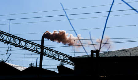 Smoke from the chimney of a chemical plant against the blue sky. The problem of environmental pollution. Ecology concept.の写真素材