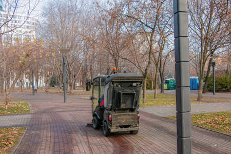 The municipal service conducts seasonal work in the park. The sweeper picks up a lot of debris. The brushes sweep the asphalt.の写真素材