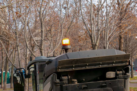The municipal service conducts seasonal work in the park. There is a signal light on the roof of the sweeper.の写真素材