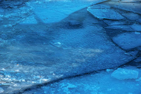 Winter nature background with blocks of ice on frozen water in spring. Abstract background of...