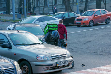 Dnepropetrovsk, Ukraine - 11.22.2021: Accident of two passenger cars due to wrong actions of a food delivery man on a moped.のeditorial素材