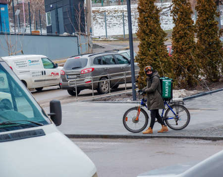 Dnepropetrovsk, Ukraine - 02.07.2022: A delivery service courier with a thermal bag on a bicycle rides around the city. home food delivery.のeditorial素材