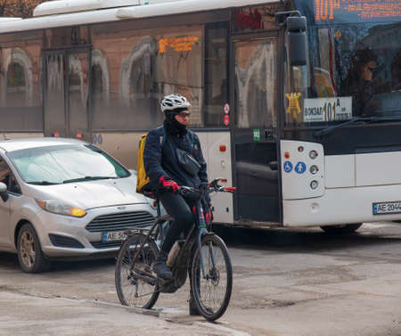 Dnepropetrovsk, Ukraine - 09/02/2022: A delivery service courier with a thermal bag on a bicycle rides around the city. home food delivery.のeditorial素材