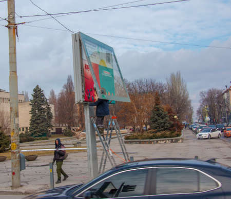 Dnepropetrovsk, Ukraine - 02.09.2022: Installation of outdoor advertising in the city. Specialists climb the stairs to the billboard. risky job. Work at height.のeditorial素材