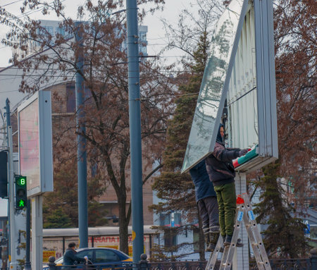Dnepropetrovsk, Ukraine - 02.09.2022: Installation of outdoor advertising in the city. Specialists climb the stairs to the billboard. risky job. Work at height.のeditorial素材