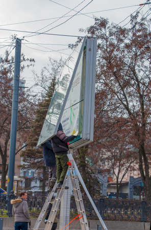 Dnepropetrovsk, Ukraine - 02.09.2022: Installation of outdoor advertising in the city. Specialists climb the stairs to the billboard. risky job. Work at height.のeditorial素材