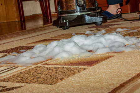 The process of cleaning the carpet with a vacuum cleaner with a water filter. Cleaning foam impregnates the dirty surface of the carpet.の写真素材