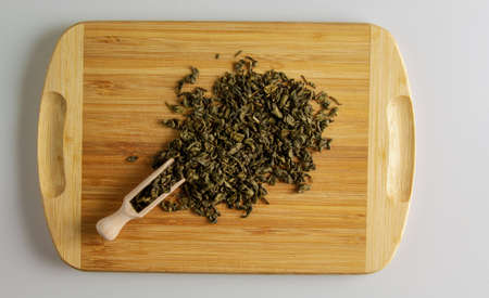 Green tea with sustain. Background of tea on a kitchen wooden board with a wooden measuring spatula.の写真素材