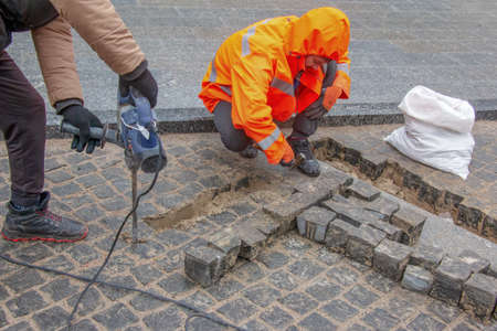 Dnipropetrovsk, Ukraine - 02.10.2022: A male worker repairs the pavement with a jackhammer. The work...