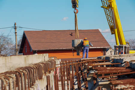 Dnepropetrovsk, Ukraine - 02.21.2022: Construction of a bypass road in the industrial area. Builder worker takes the load with concrete from the boom of the crane.のeditorial素材