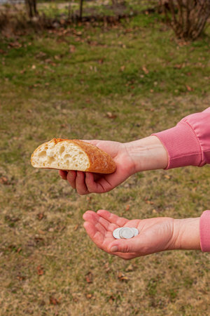 Last money for bread. Bread in the hand of a middle-aged woman. The concept of the world food crisis associated with the war in Ukraine.の写真素材