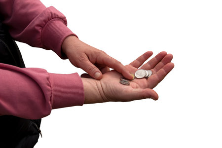 Last money for groceries. Coins in the hand of a middle-aged woman. The concept of the world food crisis associated with the war in Ukraine. isolated on white background.の写真素材