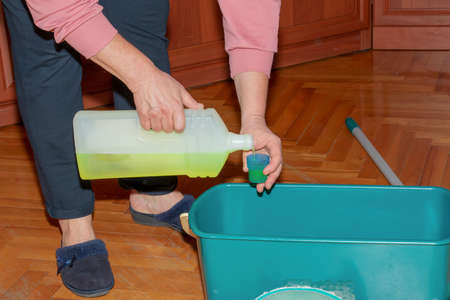 Mop your wood floor. A woman prepares a special solution for washing parquet. housekeeping concept.の写真素材