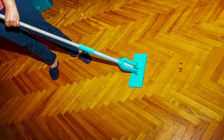 Mop your wood floor. A woman washes the parquet with a mop with a special solution. housekeeping concept.の写真素材