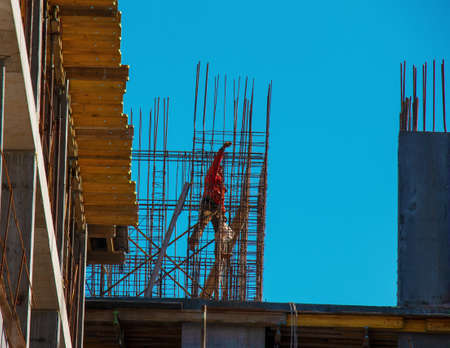 A worker prepares formwork for a modern metal-concrete structure of a residential building.
