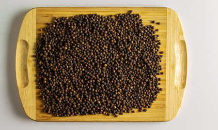 black peppercorns. Aromatic spice for food. Background of dried black pepper seeds on a wooden kitchen board.の写真素材