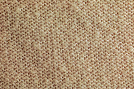 Beige knitted carpet close-up. Textile texture on a beige background. Detailed background from warm yarn. Natural wool fabric, sweater fragment.の写真素材