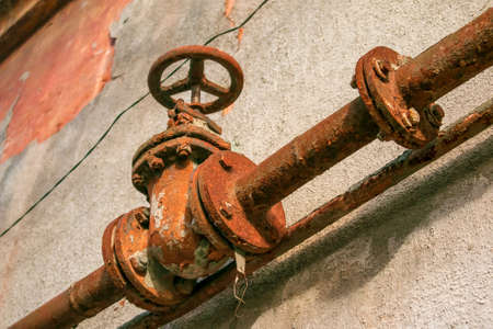 Rusty old gas tap on the background of the wall of the house.