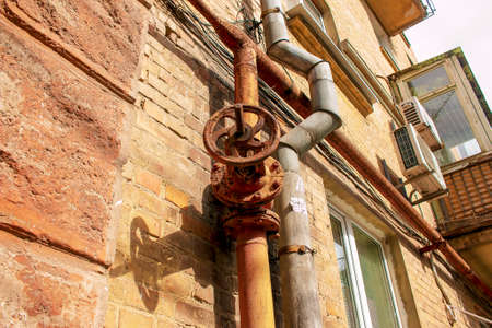 Rusty old gas tap on the background of the wall of the house.の写真素材