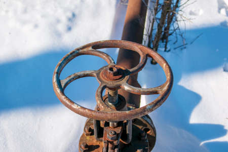 Rusty old gas tap on a background of white snow in winter.の写真素材