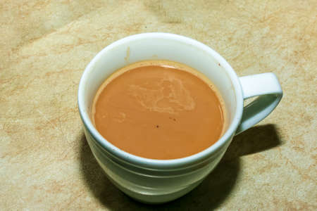 A white cappuccino mug stands on a wooden table.の写真素材