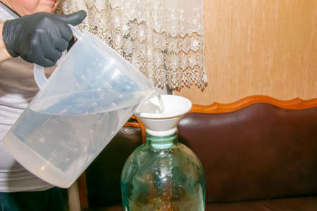The process of preparing an alcoholic drink orancello at home. A man pours alcohol into a jar of orange peel for infusion.の写真素材