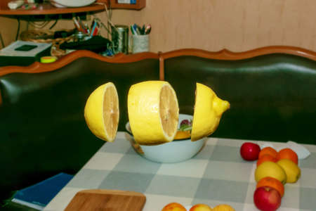 Levitation of a cut juicy lemon over the kitchen table with lying fruits.の写真素材