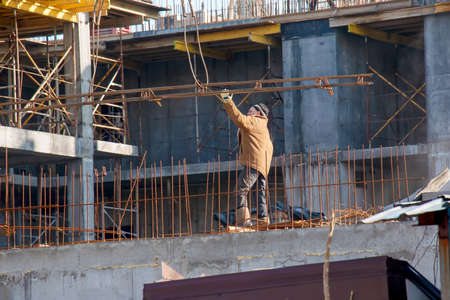 Dnepropetrovsk, Ukraine - 02.09.2022: A worker prepares formwork for a modern metal-concrete structure of a residential building.のeditorial素材