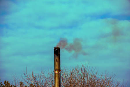 Dirty yellow smoke from a chimney against a cloudy blue sky. Ecology concept. energy crisis.の写真素材
