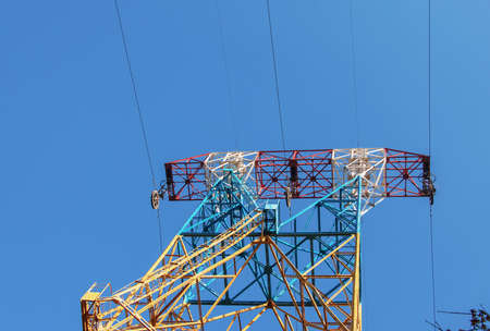 High voltage electric power lines on pylons in blue sky.