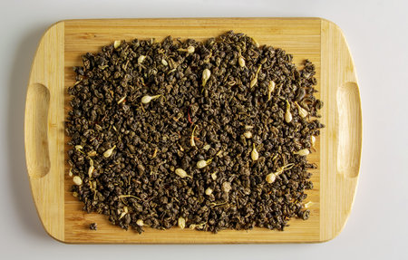 Green dry tea with jasmine flowers on a wooden board. Background and texture of dry tea.の写真素材