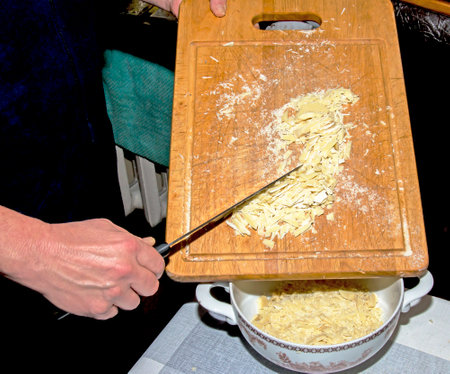 The hands of the cook pour the crushed cocoa butter into a container for making chocolate.の写真素材