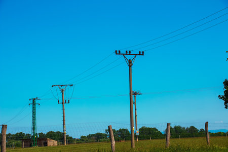 Electric pole power lines outgoing electric wires againts on cloud blue sky.の写真素材