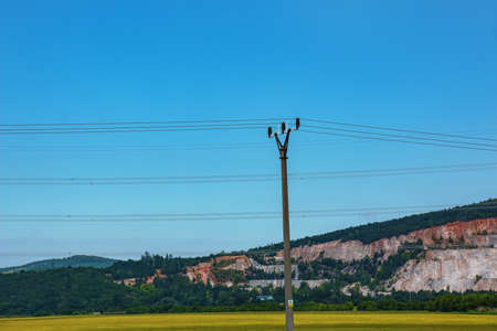 Electric pole power lines outgoing electric wires againts on cloud blue sky.