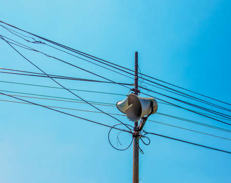 Loud Speaker or vintage white horn speaker on the pole. For public relations in the community. With wires, cables and blue skies as the background.の写真素材