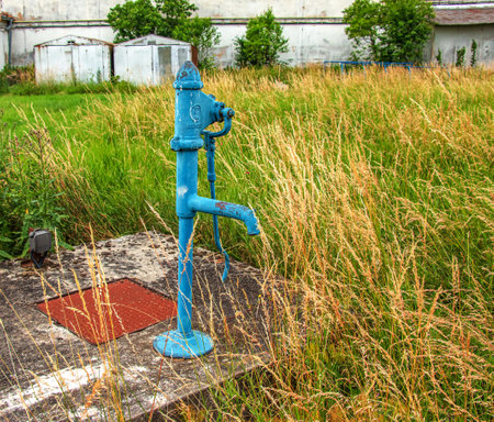 Retro borehole pump on a sunny day, old manual water pump (lever pump). Old cast iron water pump in Slovakia in the city of Nitra.の写真素材