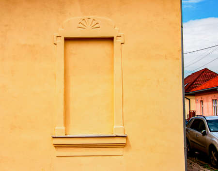 Decorative window on an old yellow plaster wall.