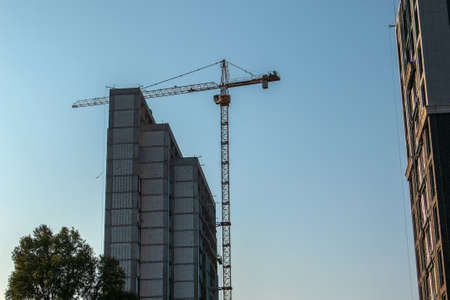Construction crane against the blue sky. The real estate industry. A crane uses lifting equipment at...