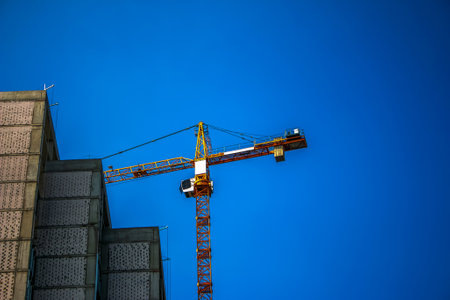 Construction crane against the blue sky. The real estate industry. A crane uses lifting equipment at...