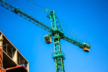 Construction crane against the blue sky. The real estate industry. A crane uses lifting equipment at...