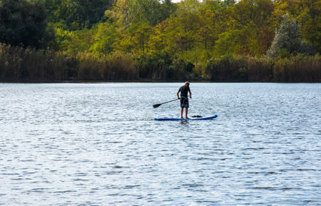 Dnipro, Ukraine - 08/09/2022: a sports man of advanced years rides a sapboard on the river. photo set. city water activities.のeditorial素材
