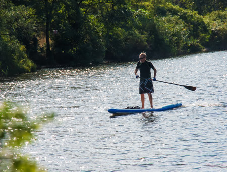 Dnipro, Ukraine - 08/09/2022: a sports man of advanced years rides a sapboard on the river. photo set. city water activities.のeditorial素材