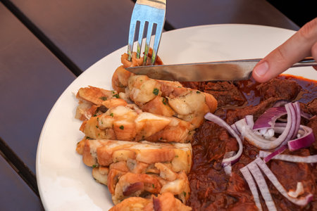 A man eats beef goulash with Czech dumplings with a knife and fork.の写真素材