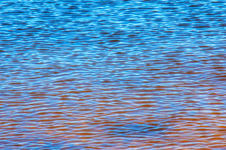 Water ripple texture background. Wavy water surface during sunset, golden light reflecting in the water.の写真素材